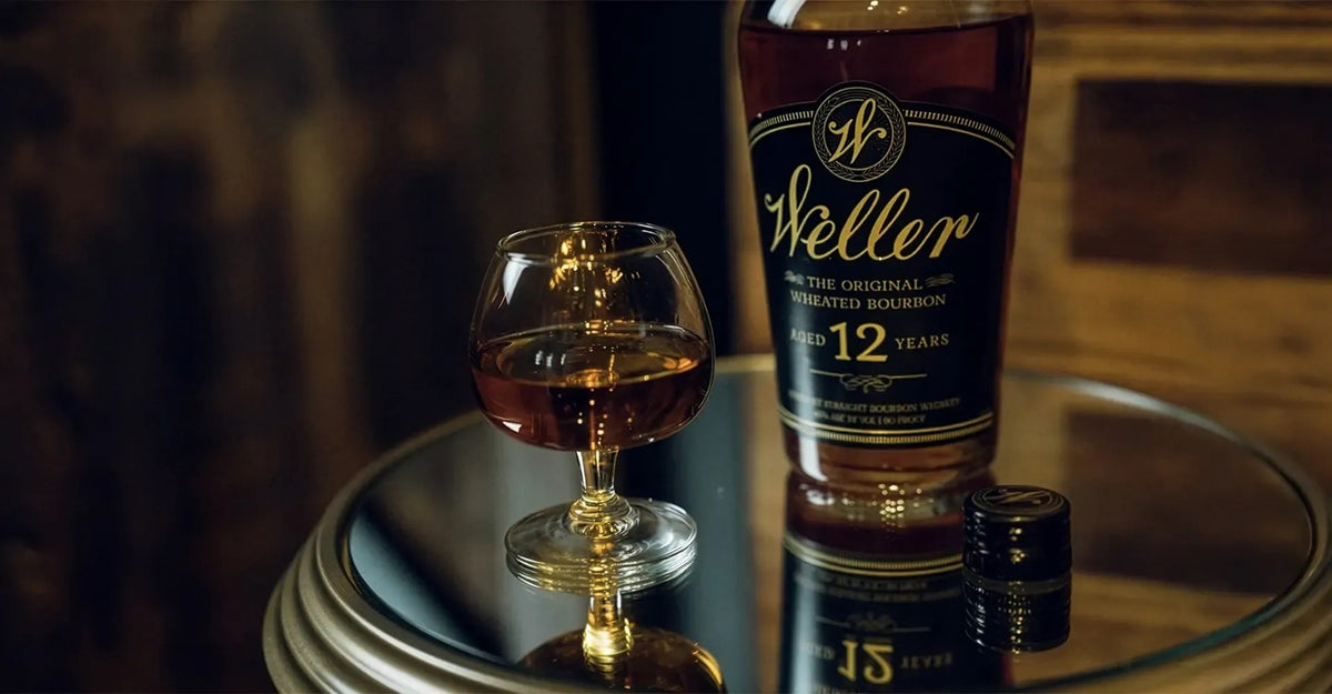 Weller 12 Year bourbon with a glass on a mirrored table